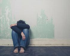 Man hunched over near a wall.