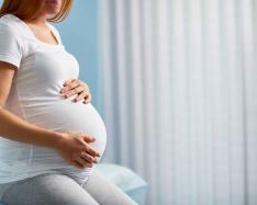 Pregnant woman with hands on her stomach.