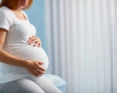 Pregnant woman with hands on her stomach. 